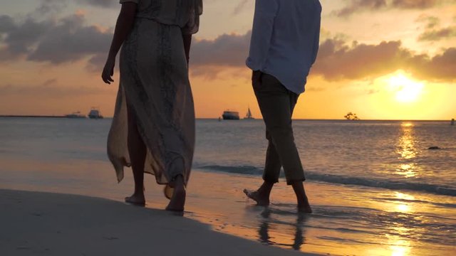 romantic beach at sunset married couple walking together barefoot 