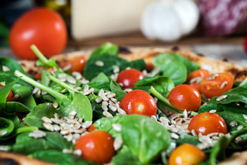Italian style pizza, fresh arugula and cherry tomatoes prepared on wooden boards