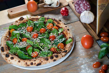 Italian style pizza, fresh arugula and cherry tomatoes prepared on wooden boards