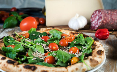 Italian style pizza, fresh arugula and cherry tomatoes prepared on wooden boards