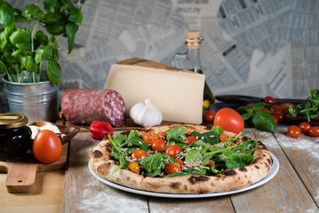 Italian style pizza, fresh arugula and cherry tomatoes prepared on wooden boards