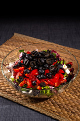 fresh salad in bowl on table in kitchen. Olives, tomatoes, lettuce. 