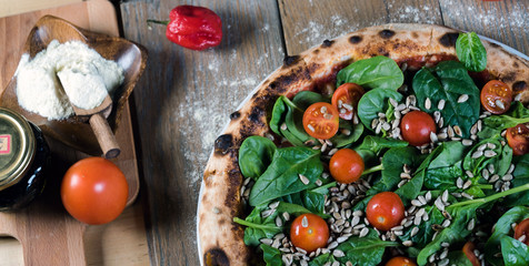 Italian style pizza, fresh arugula and cherry tomatoes prepared on wooden boards