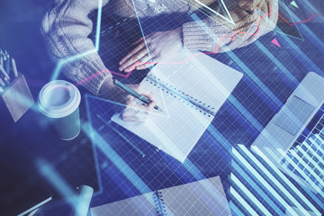 Forex graph on hand taking notes background. Concept of research. Double exposure