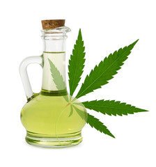 Hemp oil isolated. Sativa plant seed oil in glass bottle and fresh green cannabis leaf on white background