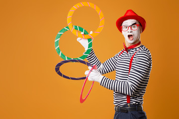 Mime man with multi-colored rings on orange background
