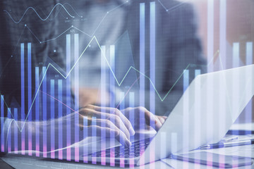 Double exposure of market chart with man working on computer on background. Concept of financial analysis.