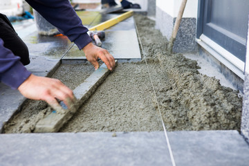 The worker puts stone slabs as the entrance stairs to the house