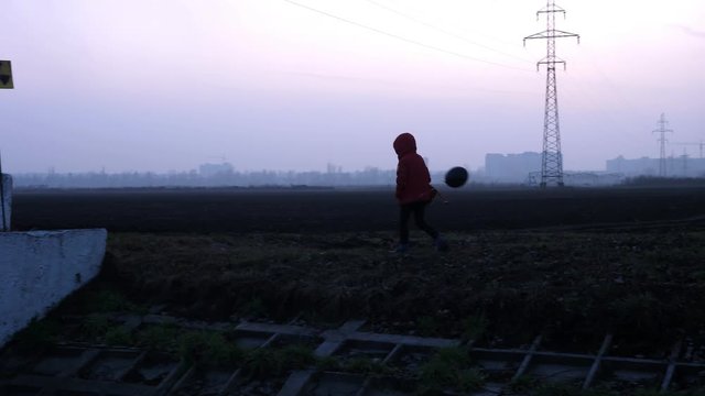 Bridge child in a respirator red jacket with a toy and a black ball, from behind the factory, radiation fear and the apocarypse, hopelessness