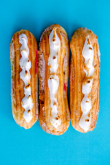Eclair cake with cocoa cream and raspberries on a blue background