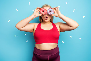 Fat girl thinks to eat donuts instead of does gym. Concept of indecision and doubt