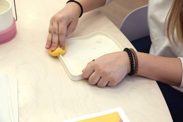 Teen girl wipes a ceramic plate with a wet sponge. Removes dust from the surface before further painting.