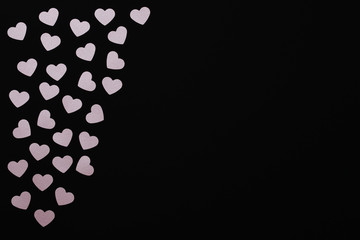 Heart background for Valentine's day greeting card with space for text. Small floating pink hearts on a black background.