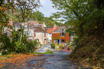Fototapeta na wymiar Idyllic French village through trees with autumn leaves on a wet road