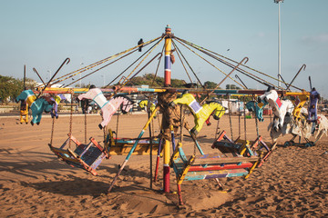 Merry go round as part of fun activities in Marina Beach, Chennai, India. Carousel with wooden horses in beach for kids fun.