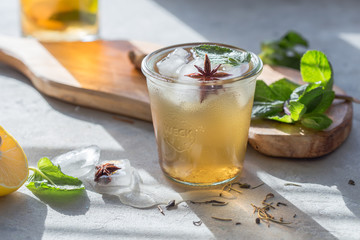 Traditional iced tea with lemon and ice in glass on a concrete rustic table. With copy space