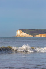 Fototapeta na wymiar Waves on the ocean with Seaford Head in Sussex behind