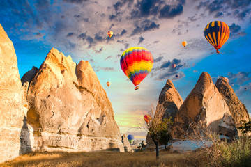 Colorful hot air balloons flying over at fairy chimneys in Nevsehir, Goreme, Cappadocia Turkey. Hot air balloon flight at spectacular Cappadocia Turkey. - obrazy, fototapety, plakaty