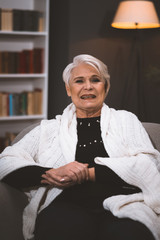 Happy Elderly Woman Sitting In Chair At Home