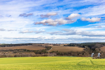 Fototapeta na wymiar Early spring landscape in South Bohemia. Green field and forest. Blue sky.