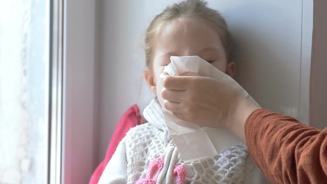 mother wipes snot with her daughter's handkerchief, child's cold