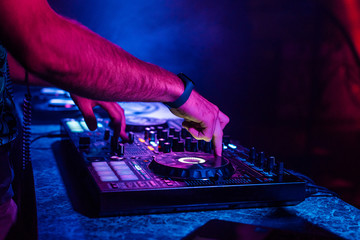 hands of a DJ playing music on a mixer at a concert
