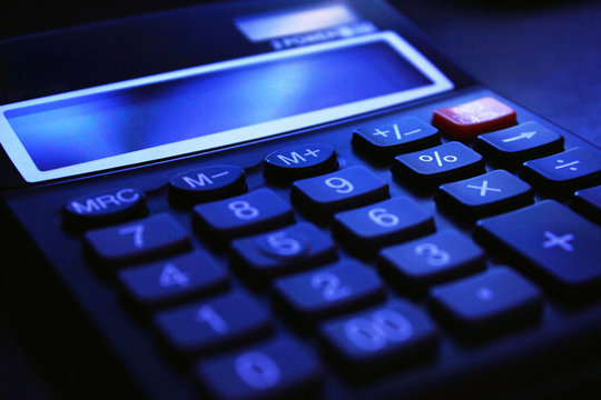 Accounting fraud. Black bookkeeping. Modern office calculator on the table on a dark background.
