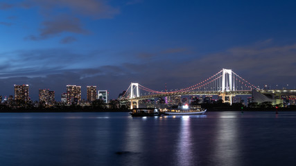Fototapeta na wymiar レインボーブリッジを背景に灯りが灯る湾岸のビル群と夜景
