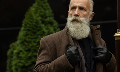 Fashionable senior man with gray hair and beard is outdoors on the street. - Powered by Adobe