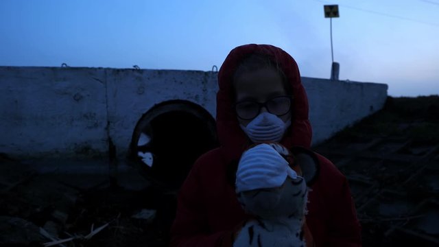 Waste ditch child in a respirator red jacket with a toy and a black ball, radiation fear and apocarypse, hopelessness