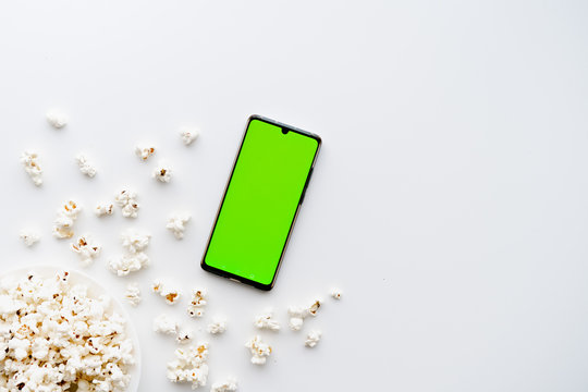 Smartphone green screen mockup and popcorn. Isolated on white background. Cinema and pastime concept. Buying tickets app, watching movies.