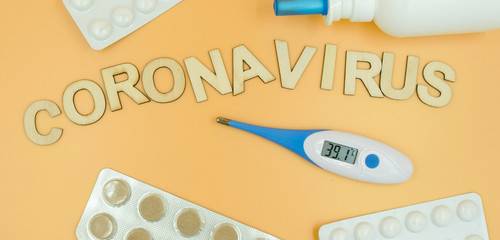 Coronavirus concept. Thermometer, tablets in a blisters and treatment medicine on a yellow background