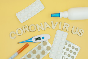 Coronavirus concept. Thermometer, tablets in a blisters and treatment medicine on a yellow background