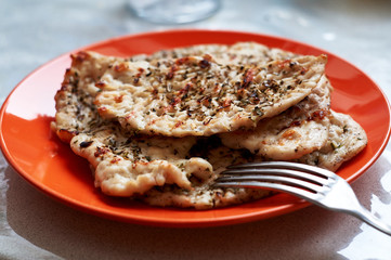 chicken fillet chop fried on a grill pan lying on a red plate