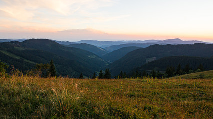 View from a meadow into a valley and over hazy hills.