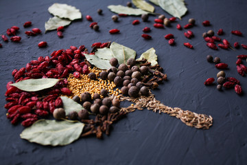 A tree lined with different spices is located on a dark surface. Culinary art.