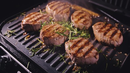 Delicious juicy meat steak cooking on grill. Prime beef fry on electric roaster, rosemary, black...