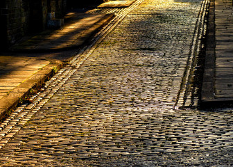 The old cobbled stones of Albert Terrace in the historic Yorkshire village of Saltaire gleam golden in the low late evening sun