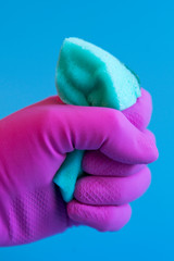 blue washcloth sponge for cleaning in the house in the hand in a pink glove. vertical photo