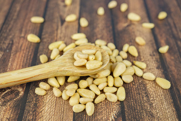 Many pine nuts with wooden spoon and wooden background