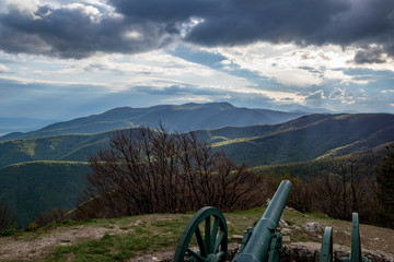 Fototapeta premium Dramatic autumn colorful view over the mountain range from near Shipka peak, Stara Planina mountain in Central Bulgaria as seen from Shipka Memorial. Moody feeling. Old Russian cannon
