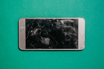 broken smartphone screen. Three-dimensional photo of broken equipment on a single-color blue mint background, top view
