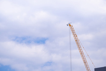 Construction site with crane on sky background. Big yellow machinery construction crane tool of building industry for heavy lifting on blue sky background. Business engineering equipment modern