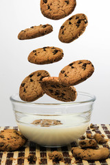 Chocolate chip cookies levitating above a bowl of milk