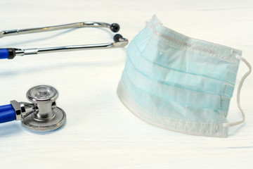 Medical protective mask and stethoscope on a white table in a doctor's office, close-up. Chinese...