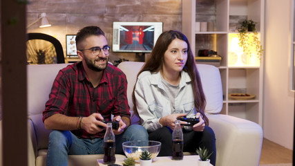 Joyful young couple sitting on the couple and playing video games