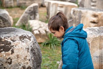 little boy looks at historical rocks from ancient years