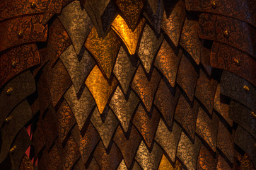 Metal scales of different shades close up. Background with golden rhombuses. Neutral dark...
