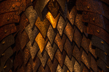 Metal scales of different shades close up. Background with golden rhombuses. Neutral dark background.