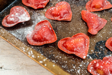 red heart-shaped tomato ravioli on an old baking sheet